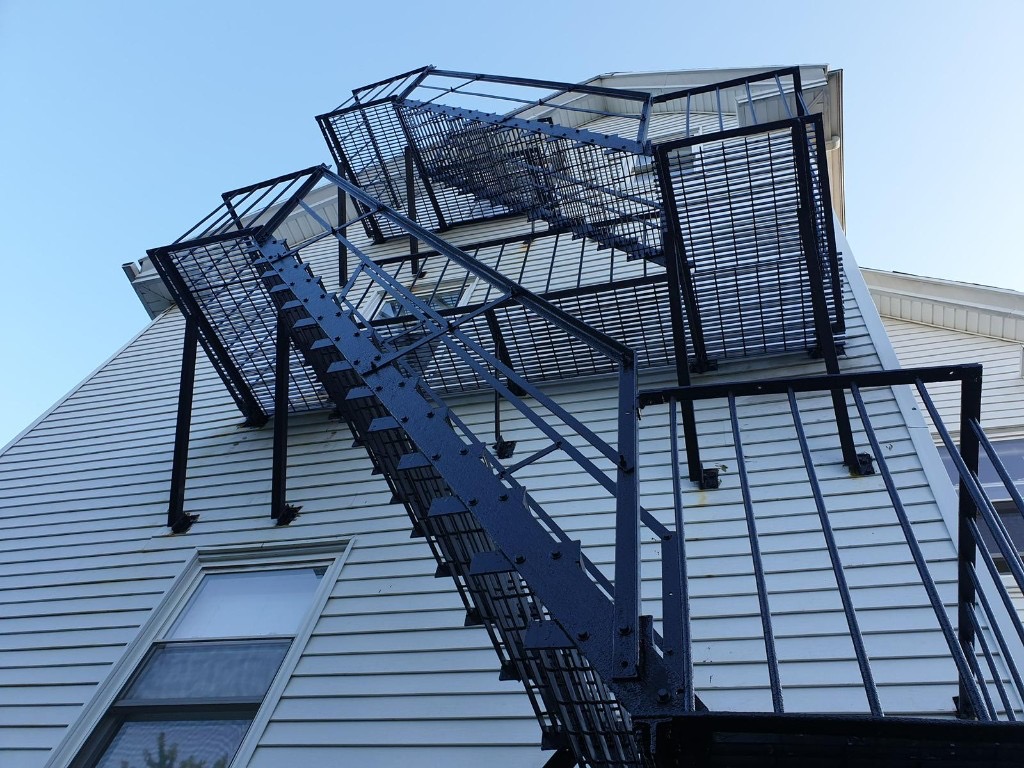 Professionally maintained black metal fire escape on a Boston building after repair and certification-ready finish